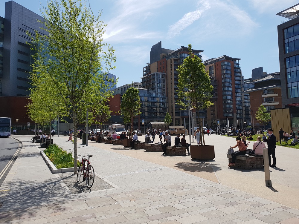 New Bailey, with tall buildings and tree lined pedestrian area with seating